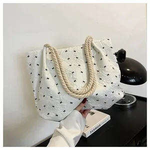 Detail of white tote bag with black bow prints and thick woven hemp rope handles
