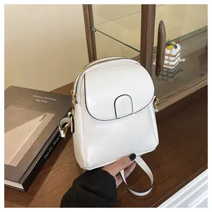 Detail of a white mini crossbody bag with black trim and gold metal zipper accents