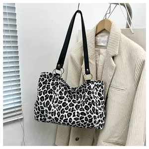 Detail of canvas tote bag with zebra pattern featuring black straps and golden rings