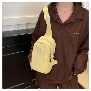 Detail view of the pale yellow crossbody chest bag with adjustable shoulder strap