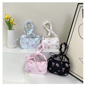 Detail of floral canvas underarm bags with ruffled handles and ribbon bows in four colors