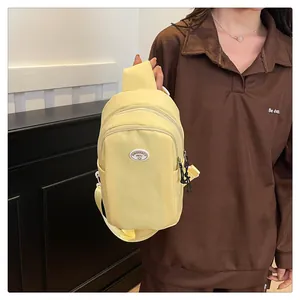 Detail showing the light yellow nylon chest bag texture with adjustable strap and logo