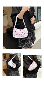 Detail view of stylish white shoulder bag with vibrant red cherry print and zipper