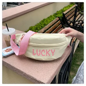 Outdoor-Aufnahme der beigefarbenen Gürteltasche mit pinkem Lucky-Print und Kontrastgurt