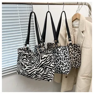 Detailed close-up of animal print canvas tote bags with leather straps and metal rings