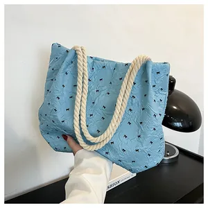 Close-up of light blue tote bag featuring black bow patterns and bubble texture fabric
