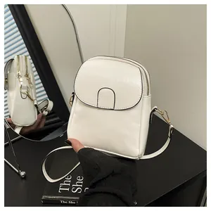 Detail view of white gloss PU leather mini crossbody bag with gold metal zippers