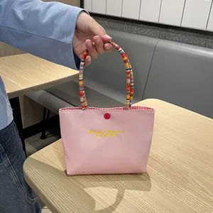 Pink canvas handbag with 'Fantasy Romance' embroidery and colorful beaded top handle