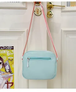 Dettaglio della borsa a tracolla in nylon azzurro con cinturino rosa sulla porta