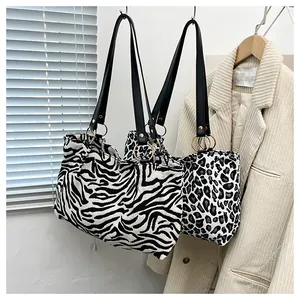 Detail view of stylish zebra and leopard print canvas tote bags with gold metal rings