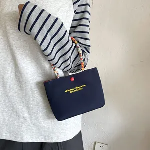 Navy nylon handbag with yellow embroidery and colorful beaded handle shown on model