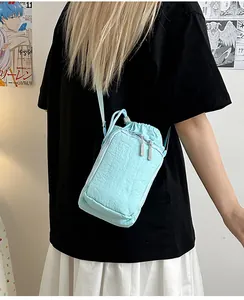Lifestyle-weergave van lichtblauwe nylon crossbodytas met trekkoord en ritszakje
