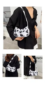 Detail shot of the black and white cow print shoulder bag with a secure zipper closure