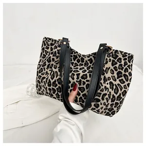 Detailed close-up of leopard print tote bag with black leather handle and gold metal rings