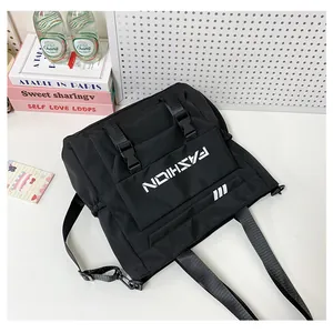 Détail du sac en toile noire avec doubles sangles, boucles et lettrage de mode