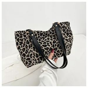 Detailed shot of leopard print canvas tote bag with black leather straps and gold rings