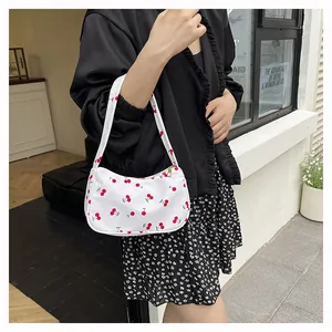 Close-up of a white underarm bag with red cherry print and silver metal zipper detail