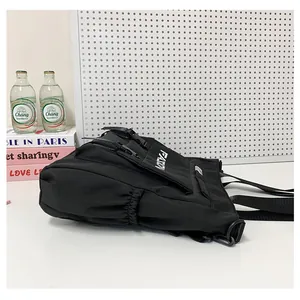 Vue détaillée du sac à bandoulière noir avec sangles à boucle et poche latérale