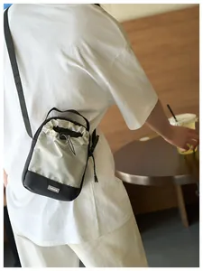 Bolso bandolera pequeño impermeable para móvil con cierre de cordón mostrado por un modelo