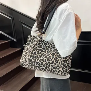Fashionable leopard print canvas tote bag with black leather straps shown on a model