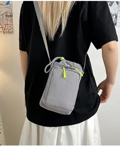 Graue Nylon-Umhängetasche mit Kordelzug und neongrünen Reißverschluss-Akzenten