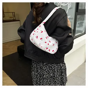 Detail of white half-moon underarm bag with red cherry prints shown on a model