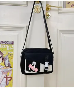 Dettaglio borsa a tracolla in nylon bianco e nero con ciondolo rosa su porta bianca