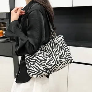Fashionable zebra print canvas tote bag with black leather straps shown on a model