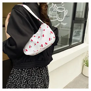 Detail of white hobo shoulder bag with red cherry print worn by a female model