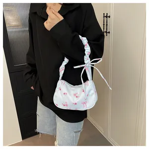 Detail of light blue floral canvas bag featuring ruched strap and elegant ribbon bow