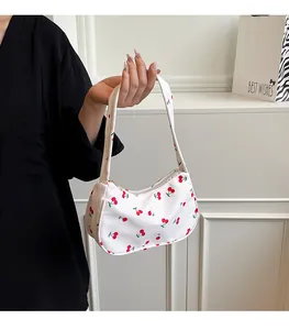 Detail of white underarm bag with red cherry prints and secure zipper closure
