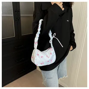 Detail of light blue floral canvas hobo bag with ruffled strap and bow accents