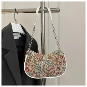 Detalle de bolso jacquard floral vintage con lazo plateado y correa de cadena