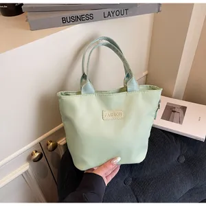 Close-up of mint green nylon handbag featuring a sleek FASHION logo tag and zip closure