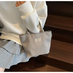 Close-up of a light grey nylon handbag with a FASHION label on a wooden staircase