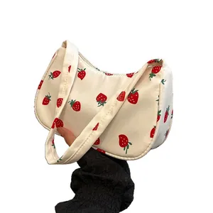 Stylish cream canvas underarm bag with all-over red strawberry print and crescent shape