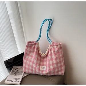 Detail der rosa karierten Canvas-Tasche mit dicken Seilgriffen und Metalldruckknopf