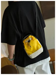 Detalle del bolso bandolera amarillo y blanco con cordón usado en la espalda del modelo