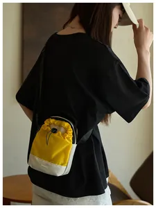 Detalle de mini bolso bandolera amarillo y negro con correa ajustable y etiqueta moda
