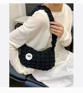Détail du sac à bandoulière noir à texture nuage avec écusson arc-en-ciel et nuage