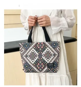 Close-up of knit tote bag featuring colorful ethnic patterns and durable black straps