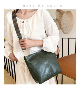 Detail of dark green tote bag featuring a colorful jacquard wide strap and golden hardware