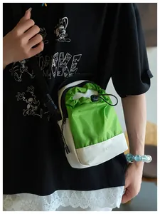 Detalle del bolso bandolera verde y blanco con cordón ajustable y etiqueta de moda