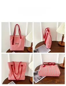 Detail view of large striped canvas tote bag with red straps and custom embroidery