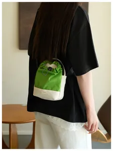 Detalle de vista trasera de un bolso bandolera impermeable verde y blanco en una modelo