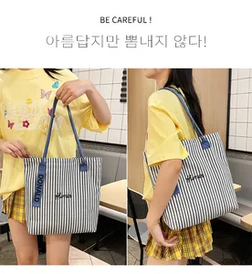 Detail of blue striped canvas tote bag showing Humin embroidery and woven Donald label