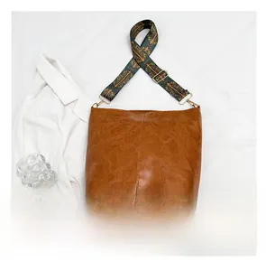 Brown vintage leather tote with geometric patterned wide strap and smartphone for size scale