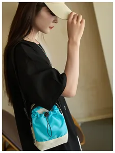 Detalle de mini bolso bandolera con cordón azul y beige con etiqueta FASHION de moda