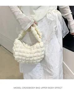 Gros plan du sac nuage plissé crème avec texture gaufrée porté par un mannequin femme
