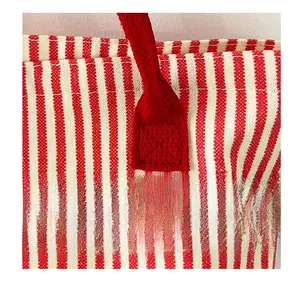 Detail view of reinforced stitching on red woven handles of a striped canvas tote bag